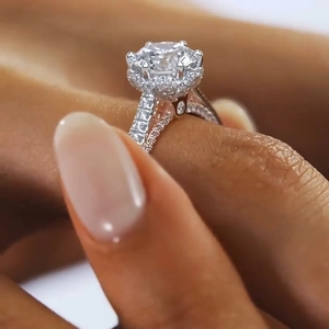 Macro shot of six-prong round cut diamond ring with pavé stones and crown base