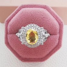 Macro detail of silver cocktail ring with yellow oval gemstone in pink velvet box