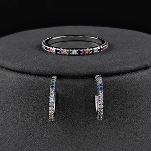 Detailaufnahme von Regenbogen-Zirkonia eingelegtem Silberring und Huggie-Ohrringe-Set