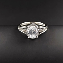 Makroaufnahme von Silberring mit gelbem Birnenschliff-Edelstein und Halo-Pavé-Band