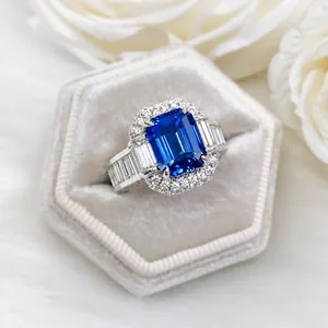 Anillo de lujo con zafiro azul talla esmeralda y halo de diamantes en caja gris