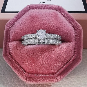 Detalle de set de anillos de boda plateados con cristal redondo en caja de terciopelo