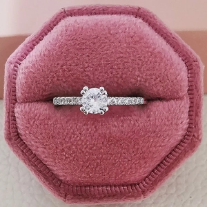 Primer plano de un anillo con circón redondo en una caja hexagonal de terciopelo rosado