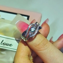 Macro shot of silver-tone ring featuring a round green gemstone with pavé crystal accents