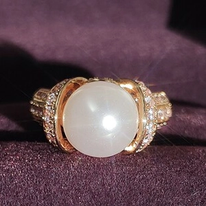 Foto macro de anillo dorado con piedra lunar central y detalles de circón pavé