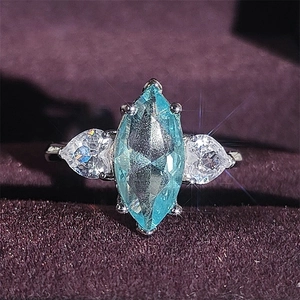Marquise-cut blue topaz ring with pear-cut white side stones on purple velvet