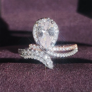Pear-shaped halo ring with two-tone crossed twisted bands in silver and rose gold
