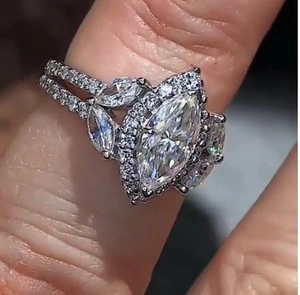 Macro view of marquise-cut zircon engagement ring with micro-pave double band on finger