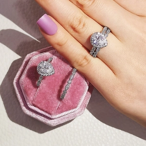 Detalle de un anillo de circonita en forma de pera en caja rosa con modelo de mano