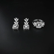 Detail eines silbernen geometrischen Schmucksets mit Smaragden und Pavé-Akzenten