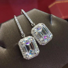 Detailed close-up of emerald-cut crystal earrings with halo setting on a jewelry display