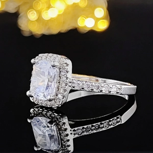 Primer plano de anillo de plata con diamante rectangular halo y banda con pavé