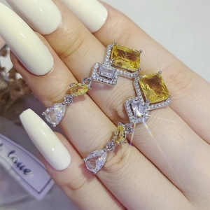 Detailed close-up of a silver drop earring with yellow rectangular stones and diamonds