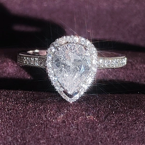 Macro di un anello di diamanti a forma di pera con castone halo su velluto viola scuro