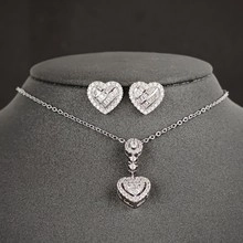 Detailed view of silver heart jewelry set with pave zircons on grey necklace display