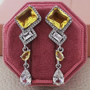 Detailed macro of long drop earrings with yellow and clear gems on red velvet box