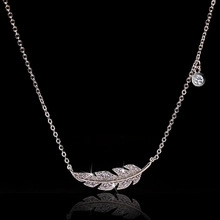 Detailed macro shot of a crystal-encrusted feather pendant necklace with a sleek chain