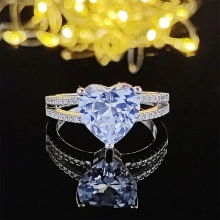 Macro shot of heart-shaped blue zircon ring with split pavé band and mirror reflection