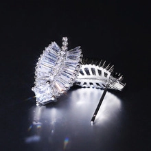 Macro shot of silver leaf earrings with shimmering baguette and square-cut zircon stones