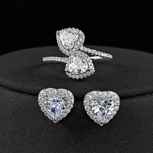 Macro detail of heart-shaped jewelry set with crystal stones on black velvet background