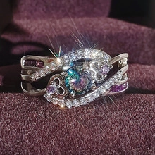 Macro di un anello d'argento con pietra centrale colorata e cuori viola laterali