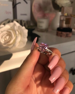 Close-up of a heart-shaped pink gemstone ring with micro-pave diamonds on the band
