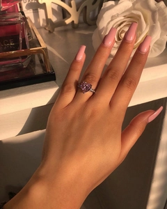 Close-up of heart-shaped pink gemstone ring on hand with elegant white roses