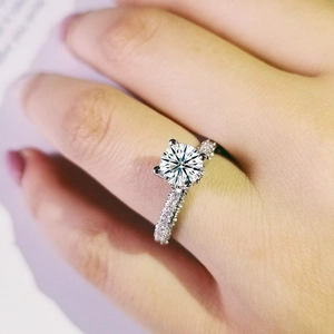 Sparkling round cut solitaire ring with pavé diamond band on female finger