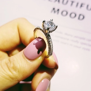 Classic round sparkling diamond engagement ring with four-prong setting and pavé band