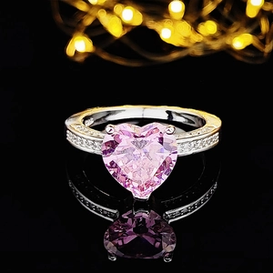 Macro shot of a heart-shaped pink gemstone ring with silver band and sparkling pavé diamonds