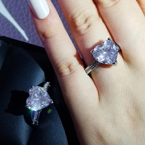 Macro shot of silver heart-shaped ring with pavé diamond band details and center stone