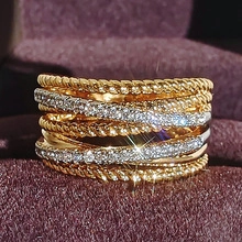 Makro-Detail eines mehrlagigen Kreuzrings mit goldener Kordel und Micro-Pavé Zirkonoxid-Steinen