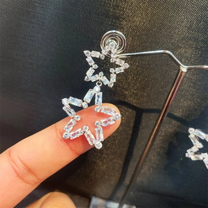 Close-up of hollow star earrings with pave set zircons and silver-tone metal details