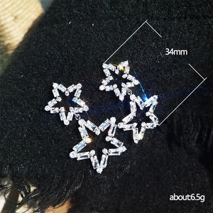 Close-up of dangling hollow star earrings with shiny rectangular crystal gemstones