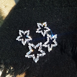 Sparkling silver star earrings with hollow frame and crystal inlay on black background