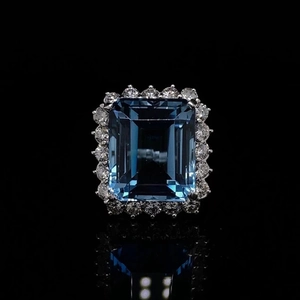 Luxuriöser Ring mit blauem Topas im Smaragdschliff und Diamant-Halo auf schwarzem Grund