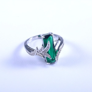 Dettaglio macro di un anello con topazio verde taglio smeraldo con accenti di foglie d'argento