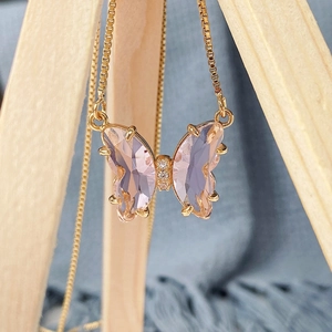 Detailed view of lavender butterfly necklace with gold box chain and crystal accents