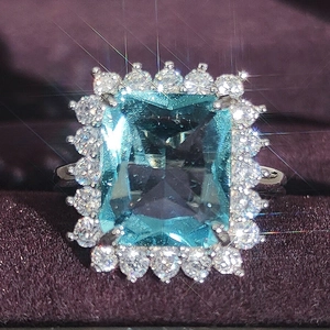 Ring mit blauem Edelstein im Radiant-Schliff und floralem Silber-Design mit Diamanten