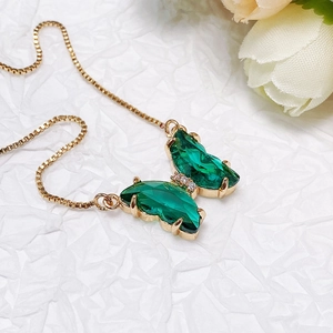 Detailed macro view of crystal butterfly pendant with emerald-cut glass and gold box chain