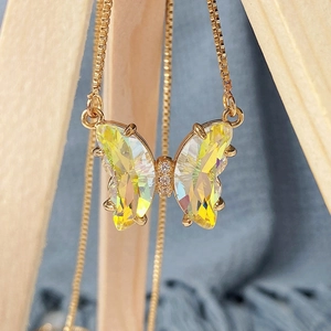 Macro detail of butterfly pendant with aurora crystal facets and gold box chain