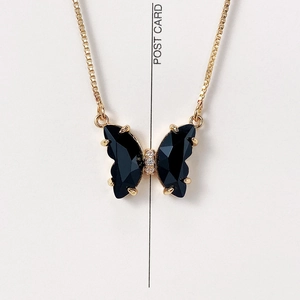 Detail view of crystal butterfly pendant with black faceted stones on a gold box chain