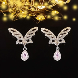 Détail des boucles d'oreilles papillon avec goutte en zircon rose sur fond noir élégant