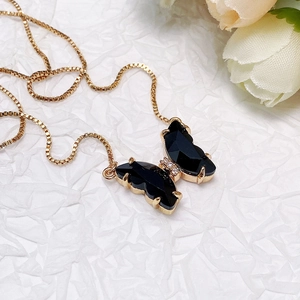 Detail of golden box chain with black butterfly pendant and micro-set zirconia crystals