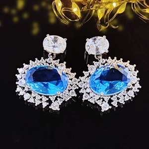 Vue détaillée des boucles d'oreilles ovales bleu saphir avec halo de zircon blanc et argent