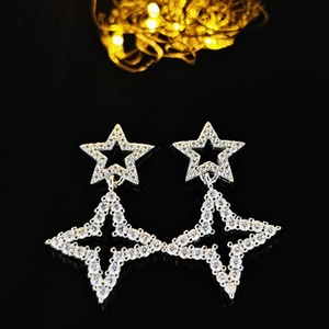Détail de boucles d'oreilles étoiles avec zircons étincelants sur fond noir élégant
