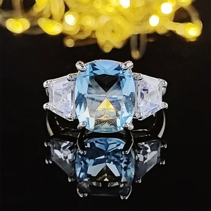 Anello di lusso con cristallo blu mare quadrato e pietre laterali a forma di scudo