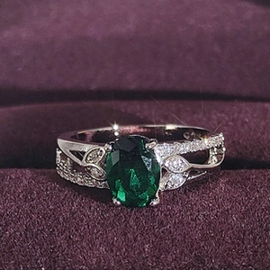 Dettaglio di un anello in argento con gemma verde ovale e accenti di foglie in zircone