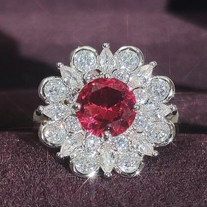 Macro di un anello a fiore con zircone rosso scuro e pietre preziose bianche