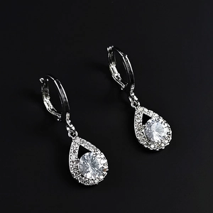 Détail de boucles d'oreilles larmes en argent avec pavé de cristaux et diamant central